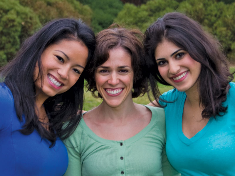Three lady friends smiling outside.